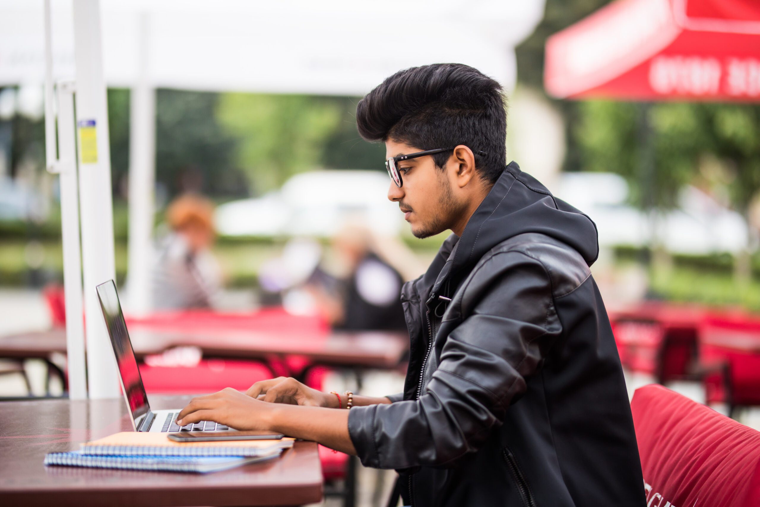 Indian Man using laptop in outdoor street cafe